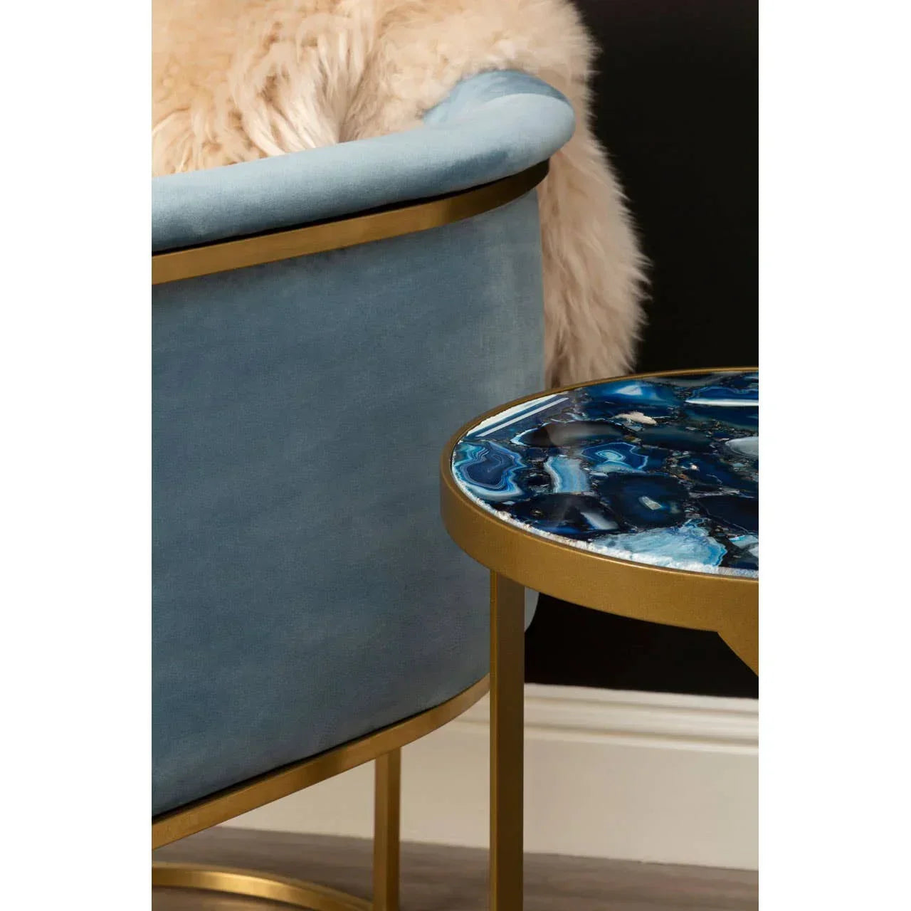 Blue velvet accent chair with gold frame beside blue agate top side table