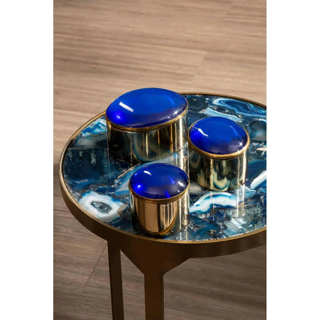 Round side table with blue agate stone top and gold metal base on wooden floor