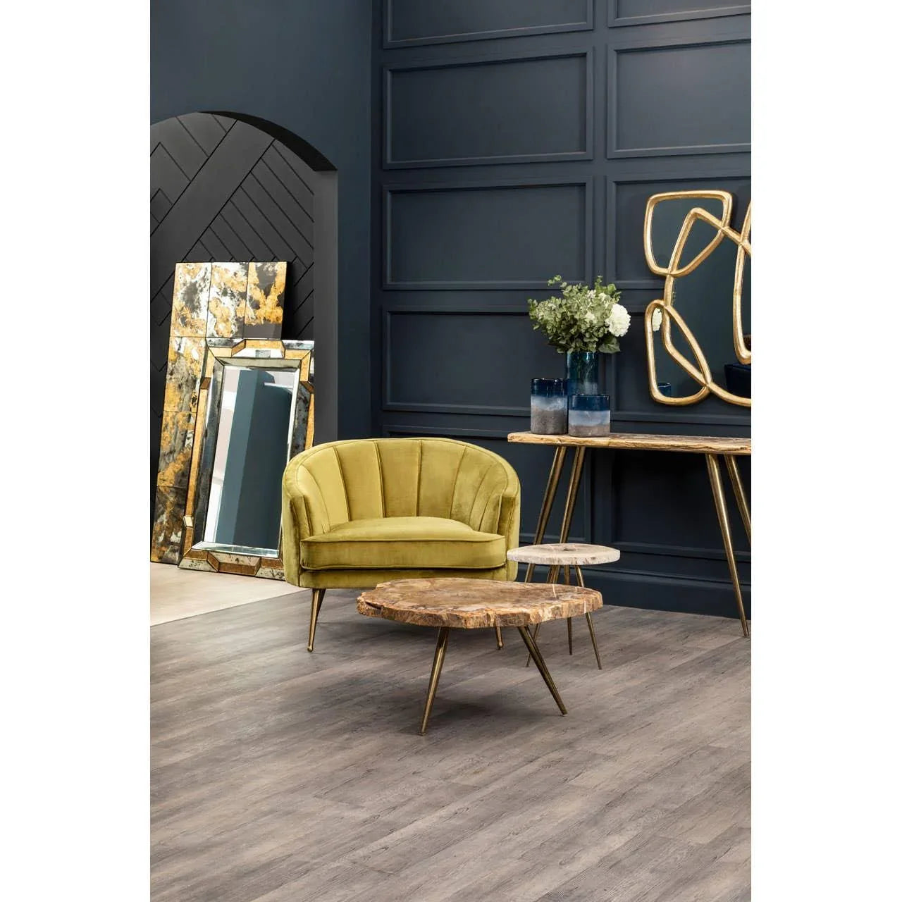 Olive green velvet accent chair with gold legs beside modern wood coffee tables in living room