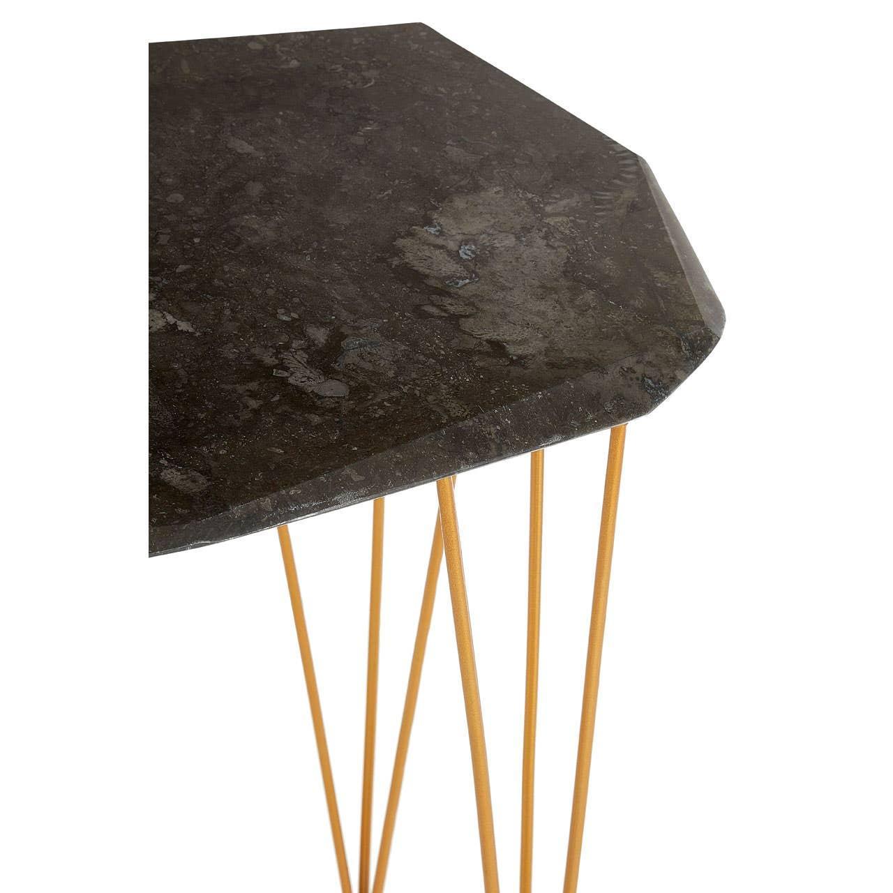 Black marble side table with gold metal legs, close-up of corner and textured top
