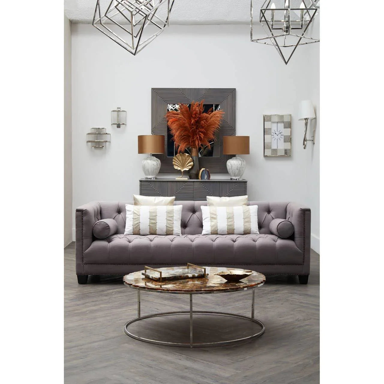 Grey tufted sofa with striped cushions and round coffee table in modern living room