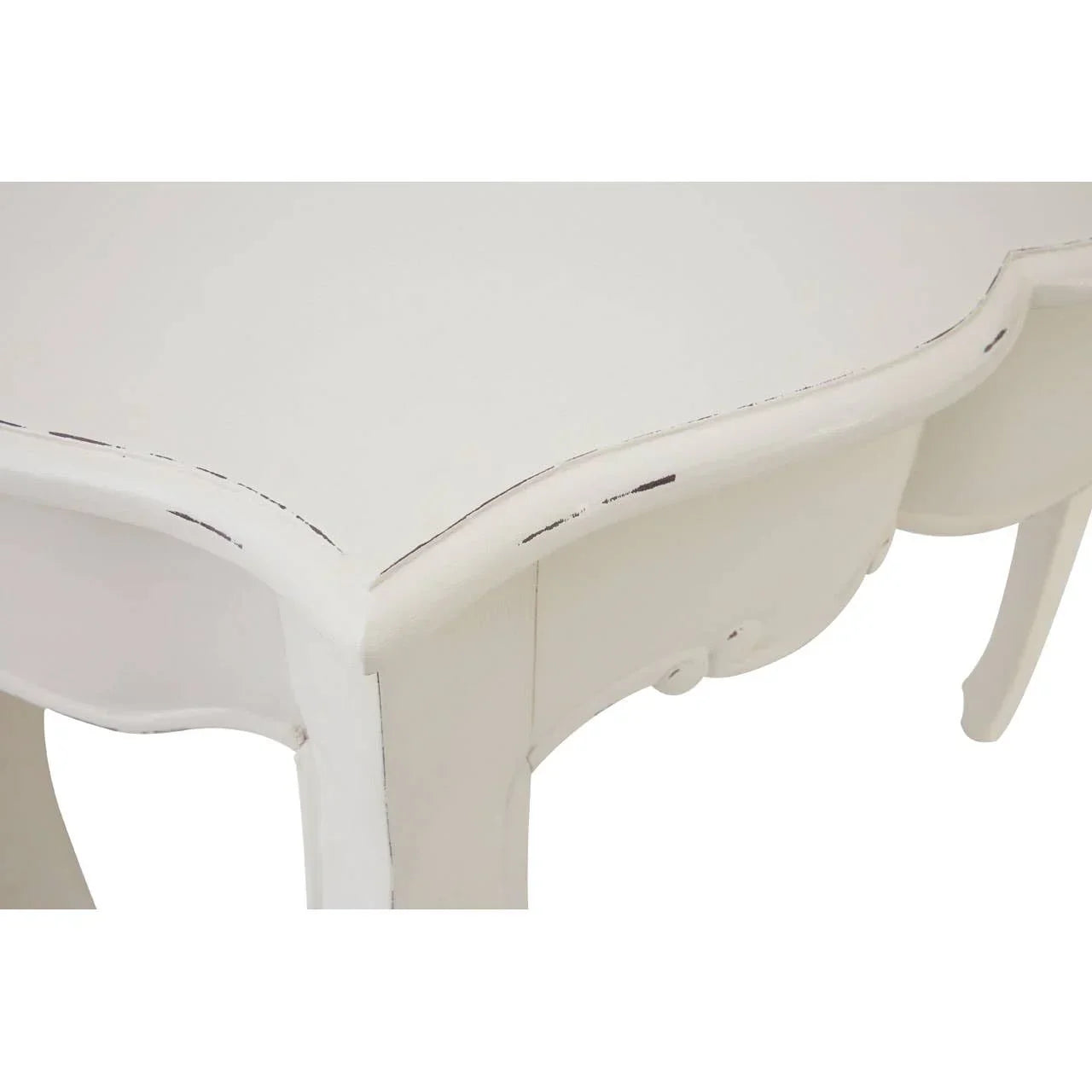 Closeup of white wooden dining table with distressed edges and carved details