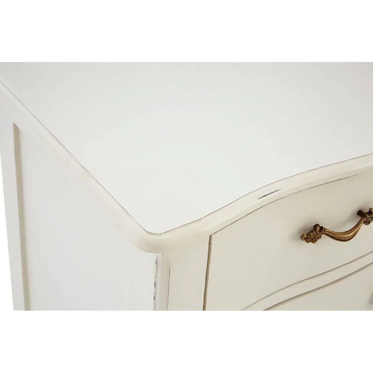 Closeup of white wooden dresser corner with curved edge and brass drawer handle