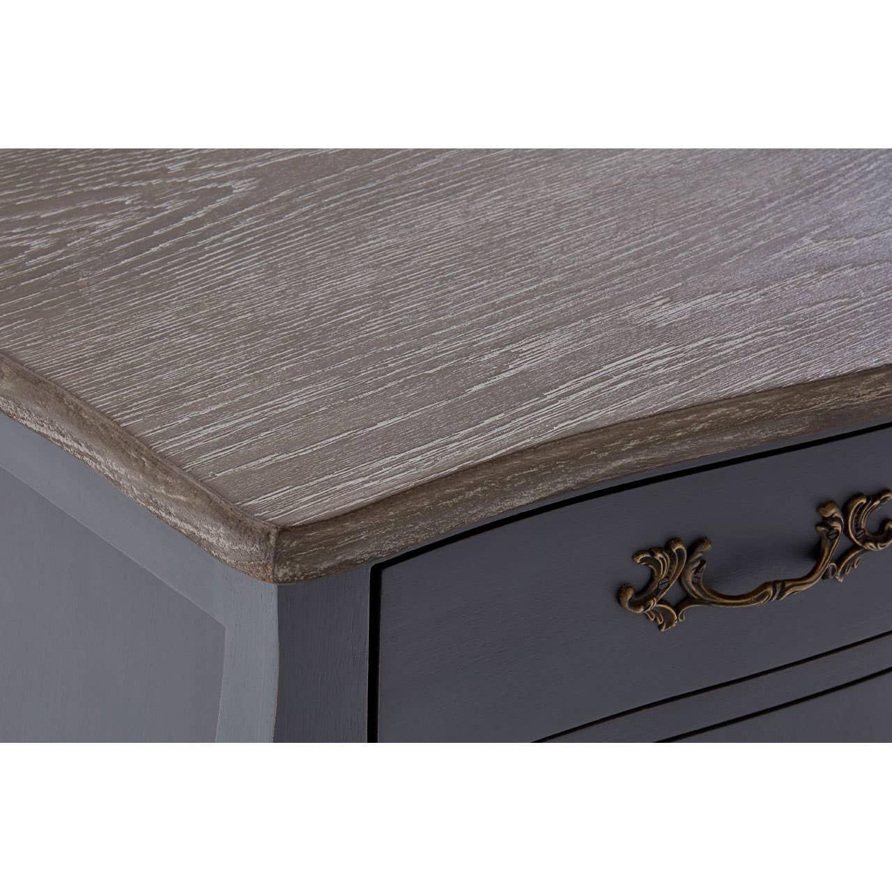 Close-up of wooden chest of drawers with grey top and ornate brass handle detail