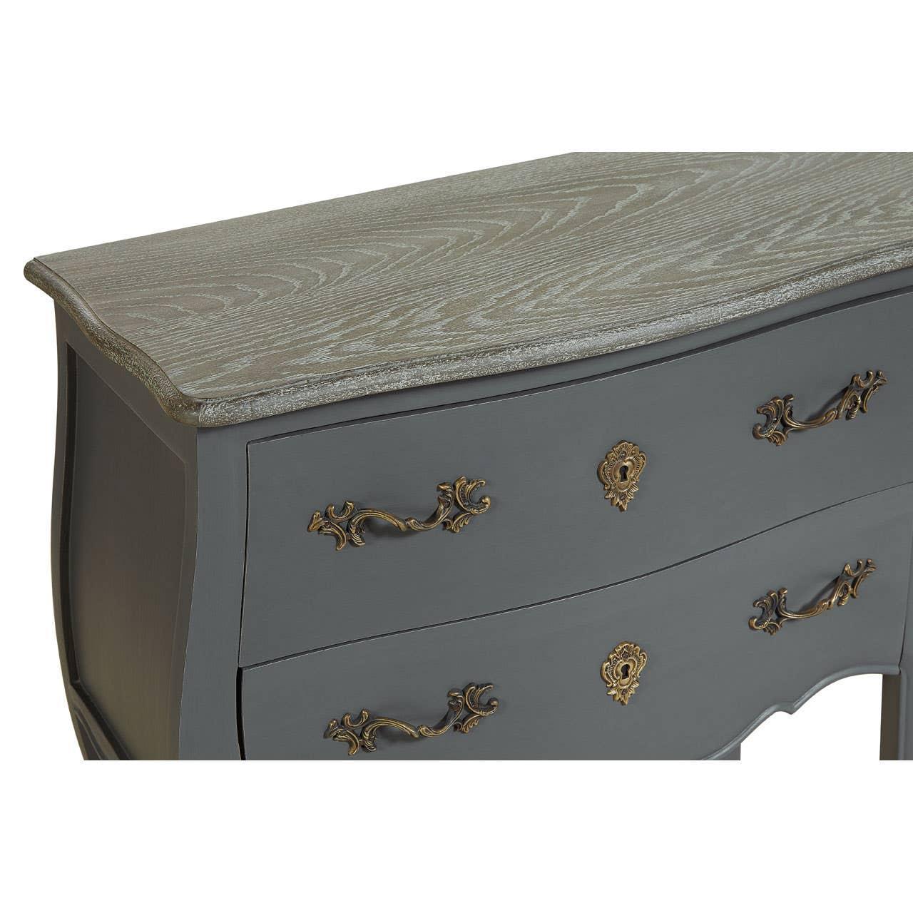 Grey wooden chest of drawers with ornate brass handles and textured wood grain top