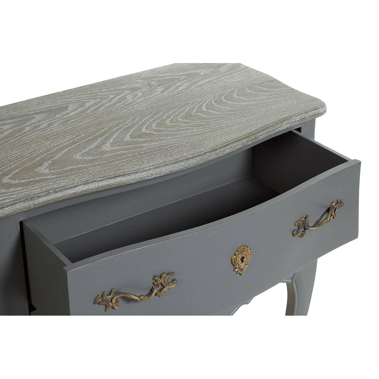 Grey wooden drawer chest with brass handles and open drawer, close-up of wood grain top