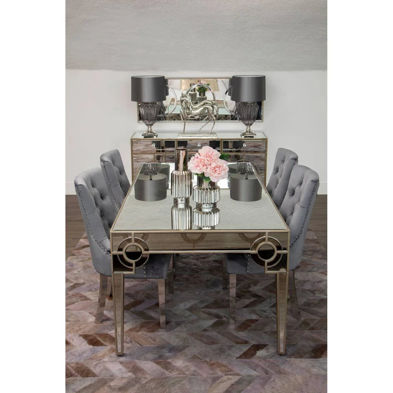 Mirrored dining table with grey velvet chairs and decorative vases on modern rug