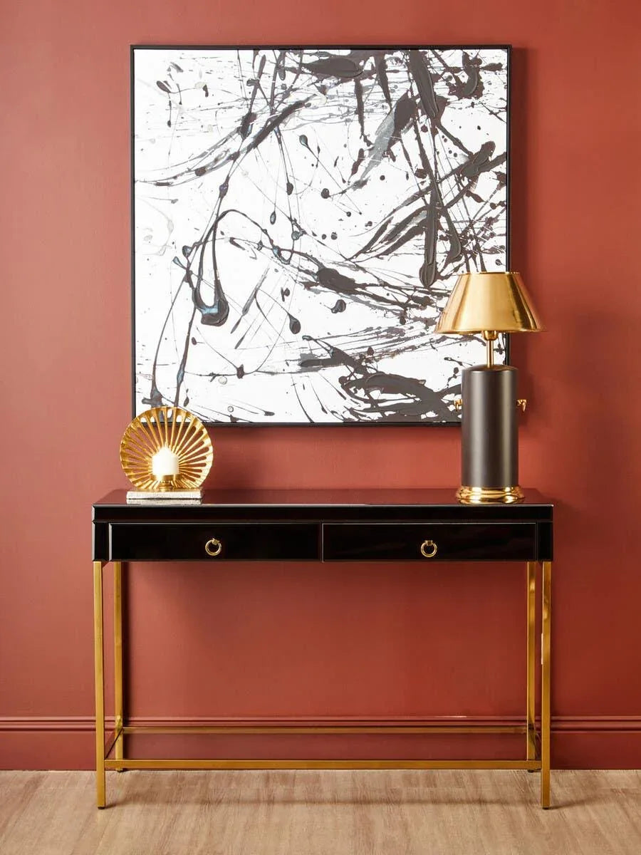 Black and gold console table with gold lamp and decor against terracotta wall