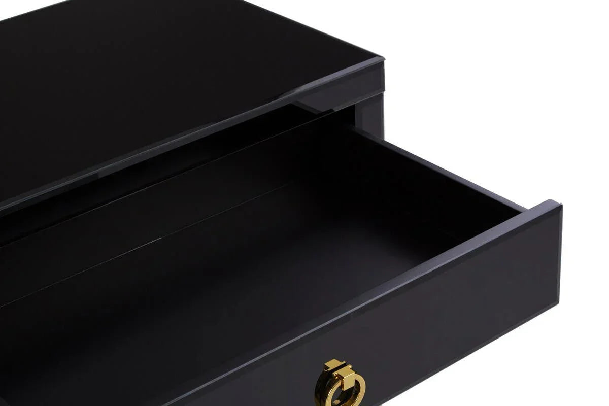 Black bedside table with open drawer and gold handle, close-up on storage space