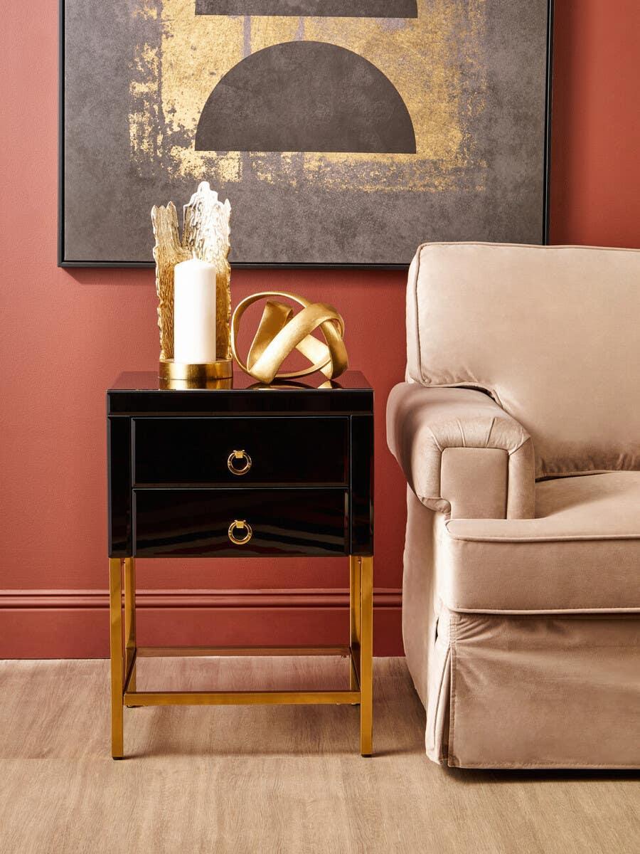 Black and gold side table with two drawers beside beige sofa in modern living room