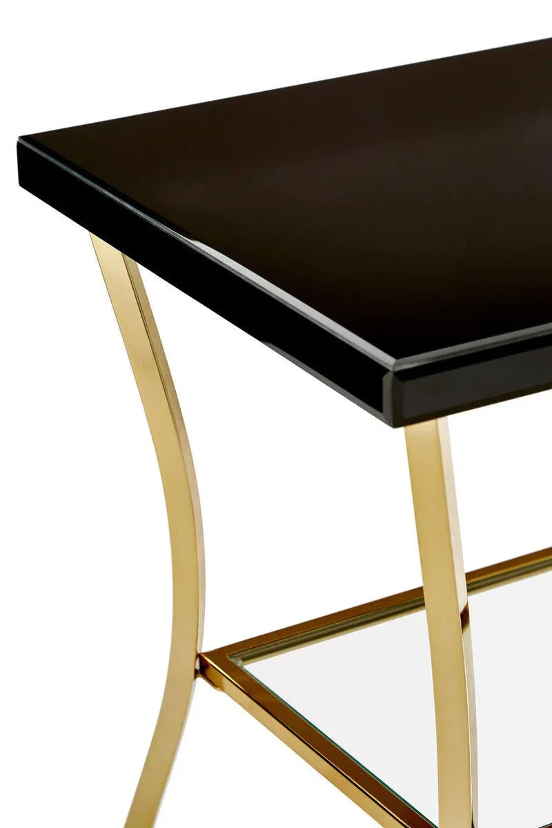 Black glass coffee table with gold metal legs and lower glass shelf, side angle close-up