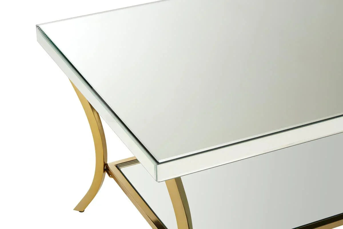 Mirrored coffee table with gold metal legs and glass top, corner angle view
