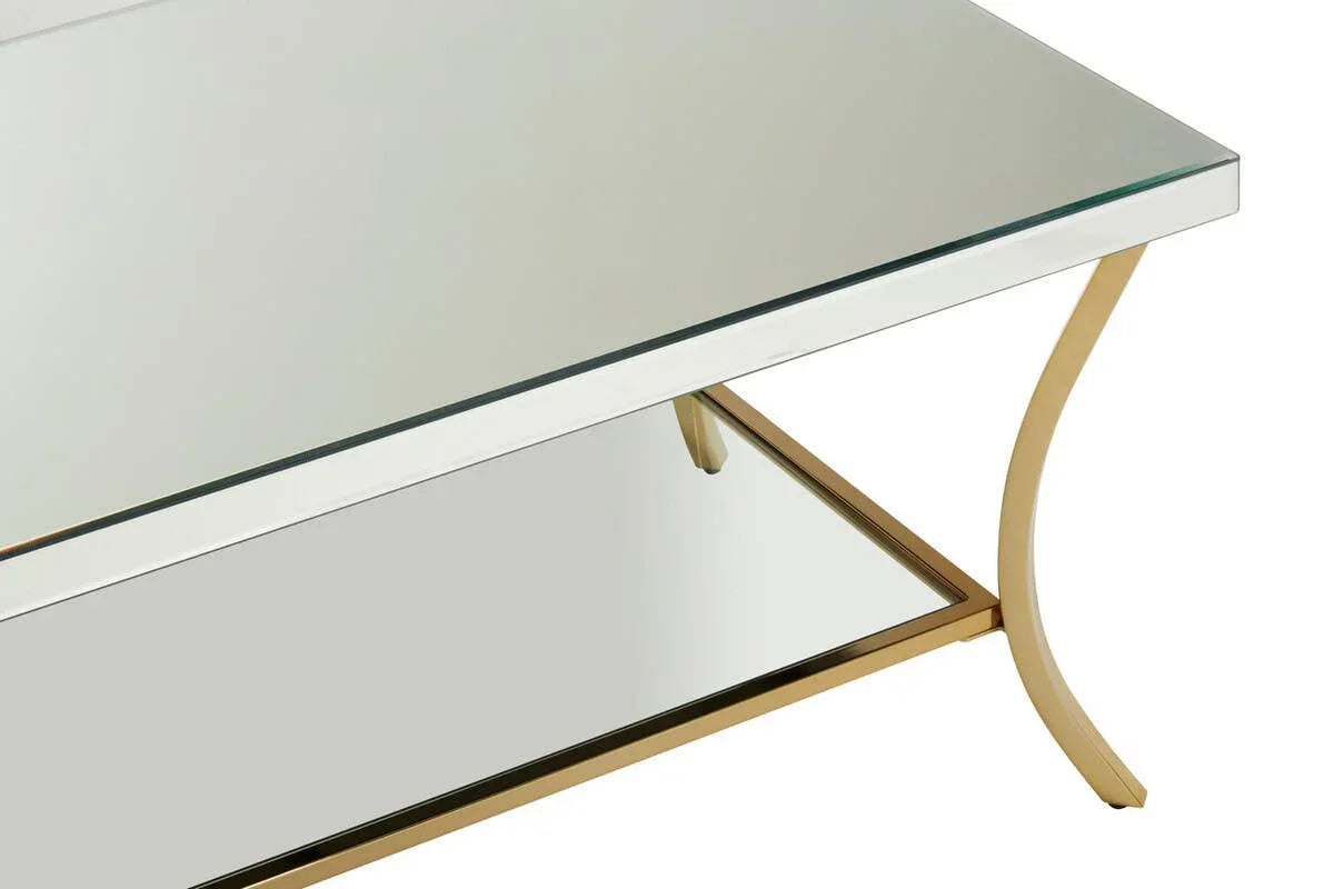 Glass coffee table with gold metal legs and mirrored lower shelf, closeup angle