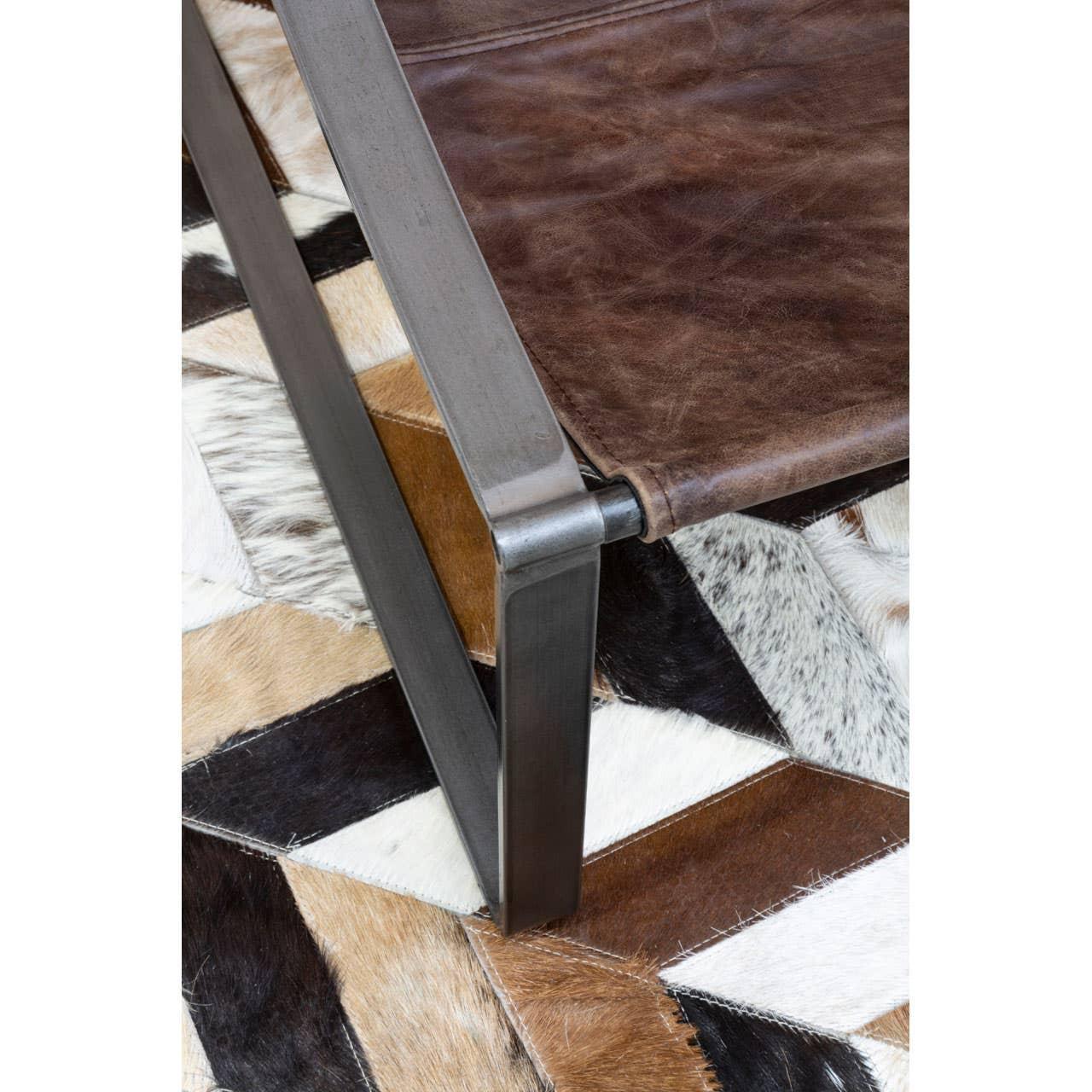 Brown leather chair with metal frame on geometric cowhide rug