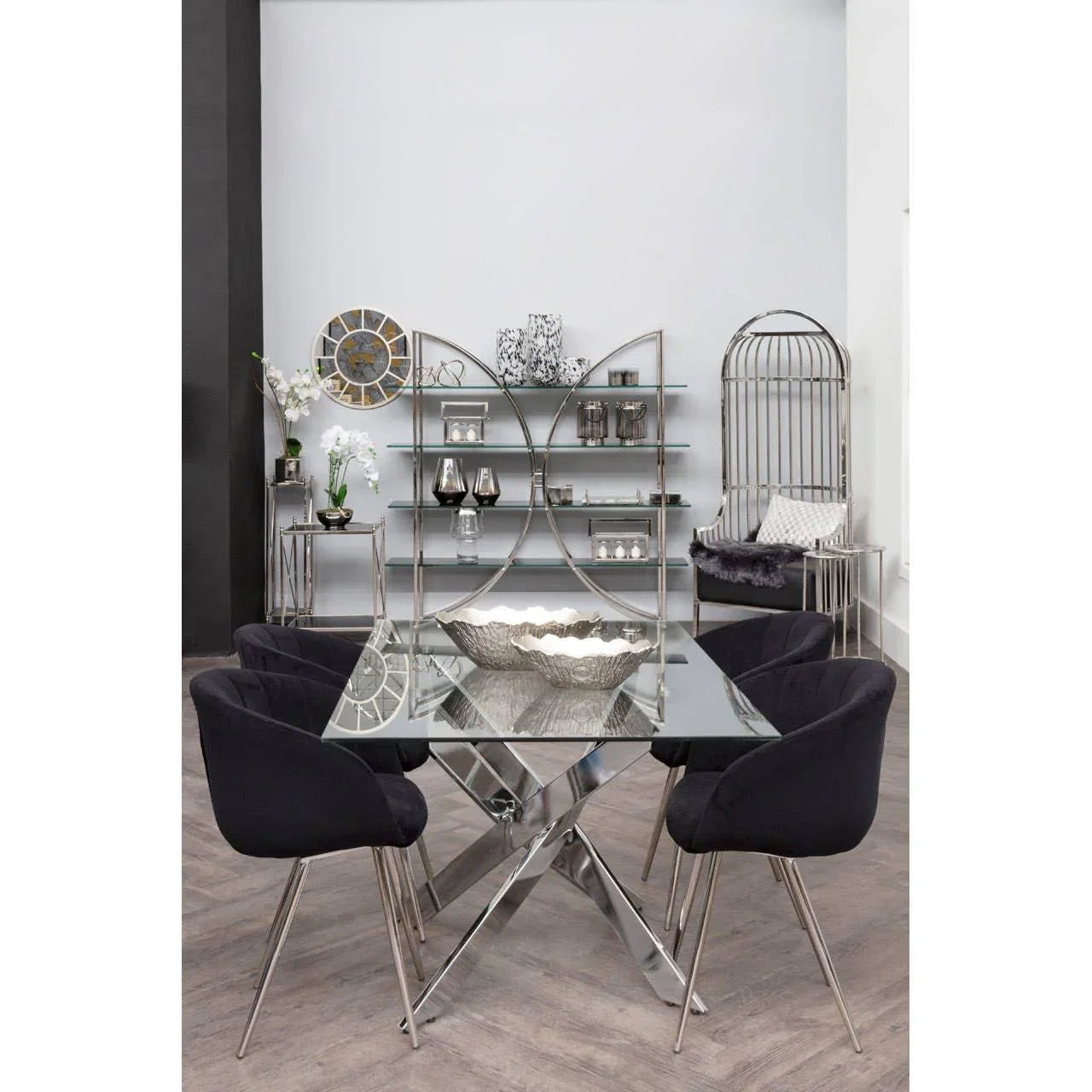 Glass dining table with chrome legs and four black chairs in modern dining room