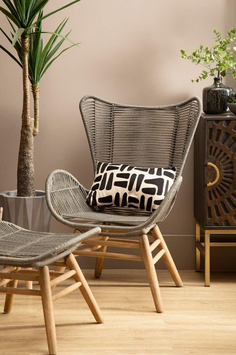 Modern rattan accent chair with matching footstool and geometric cushion in living room