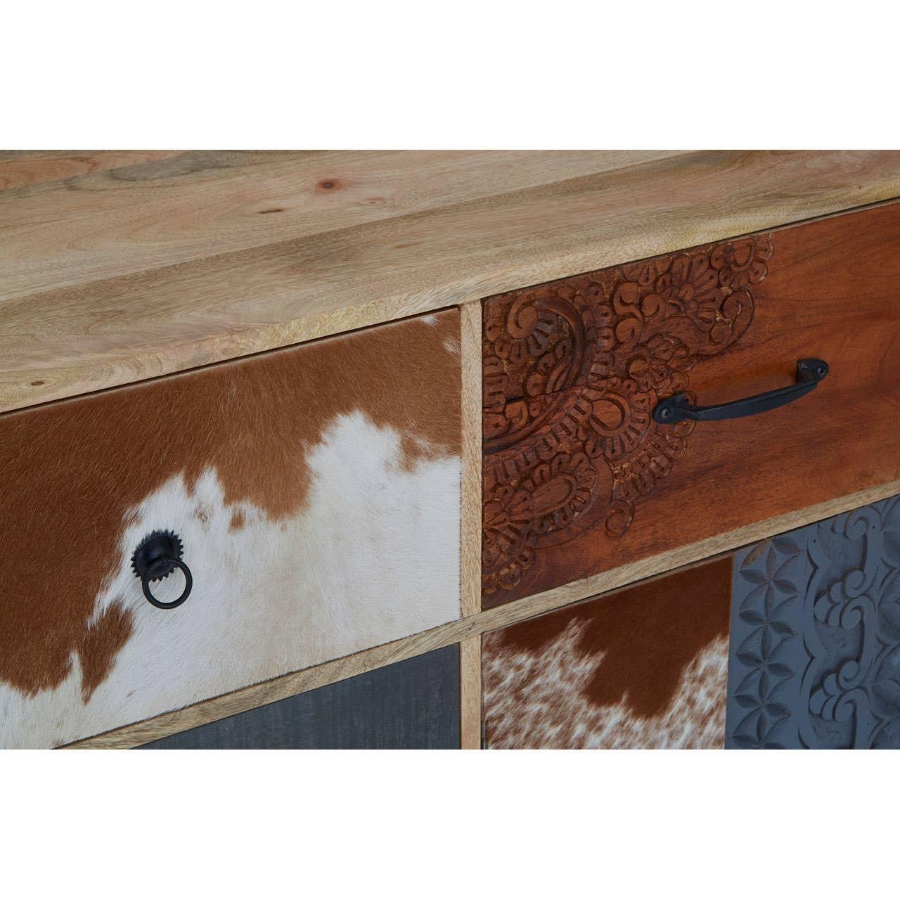 Closeup of wood and cowhide chest of drawers with carved and embossed drawer fronts