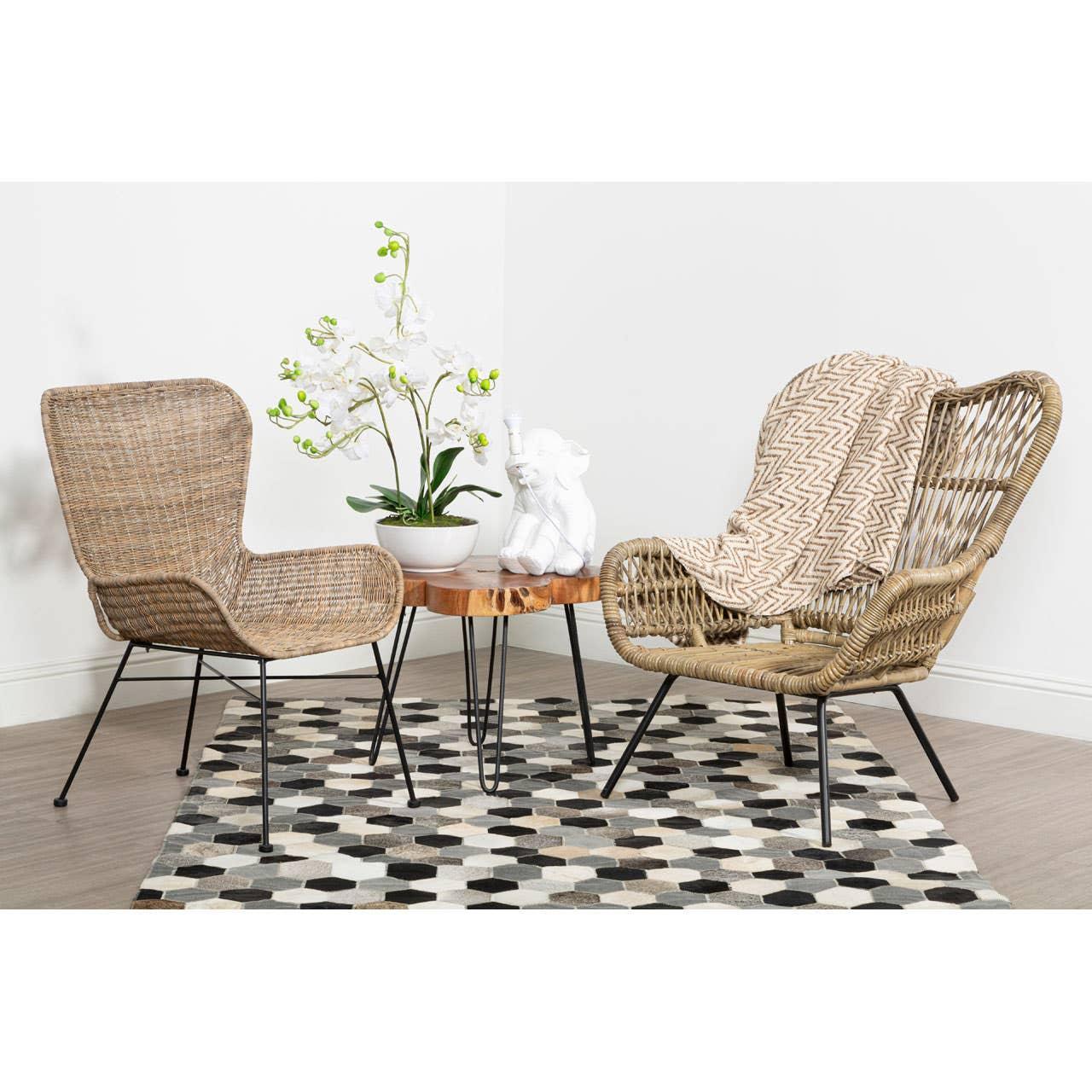 Rattan armchairs and wood side table on geometric rug in a modern living room corner
