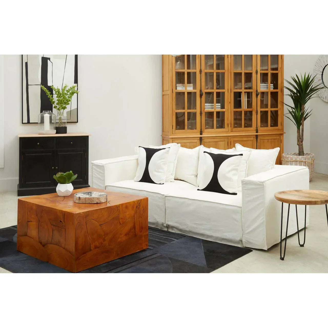 White fabric sofa with monochrome cushions beside wooden coffee table in modern living room