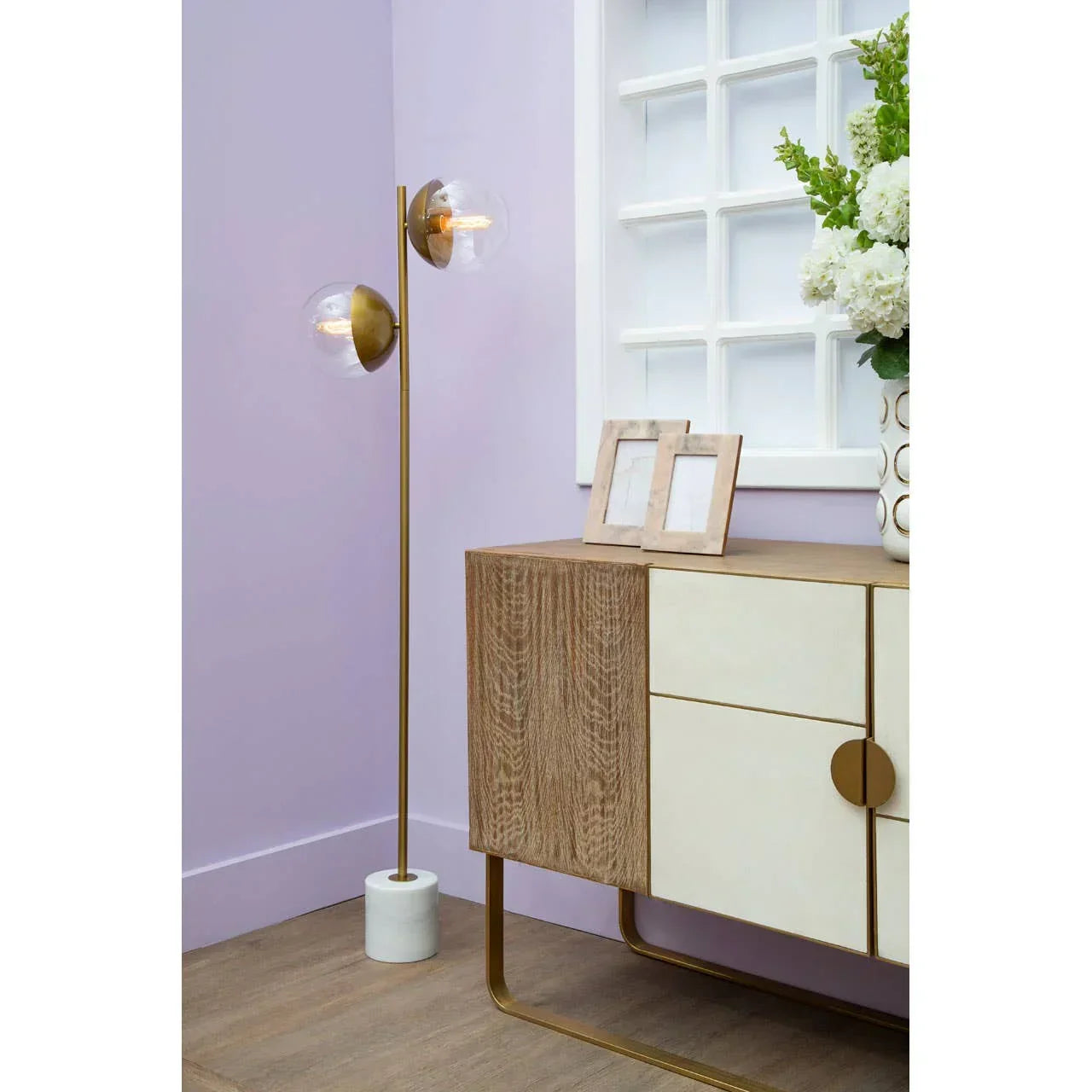 Modern wooden sideboard with cream panels beside floor lamp and white flower vase