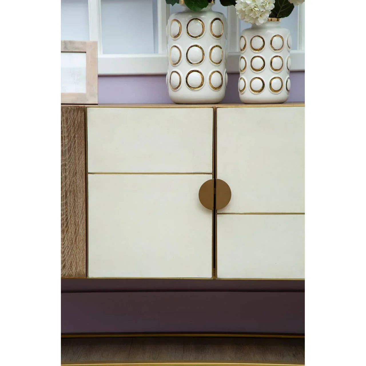 Modern sideboard with cream and wood finish, circular brass handle, vases on top