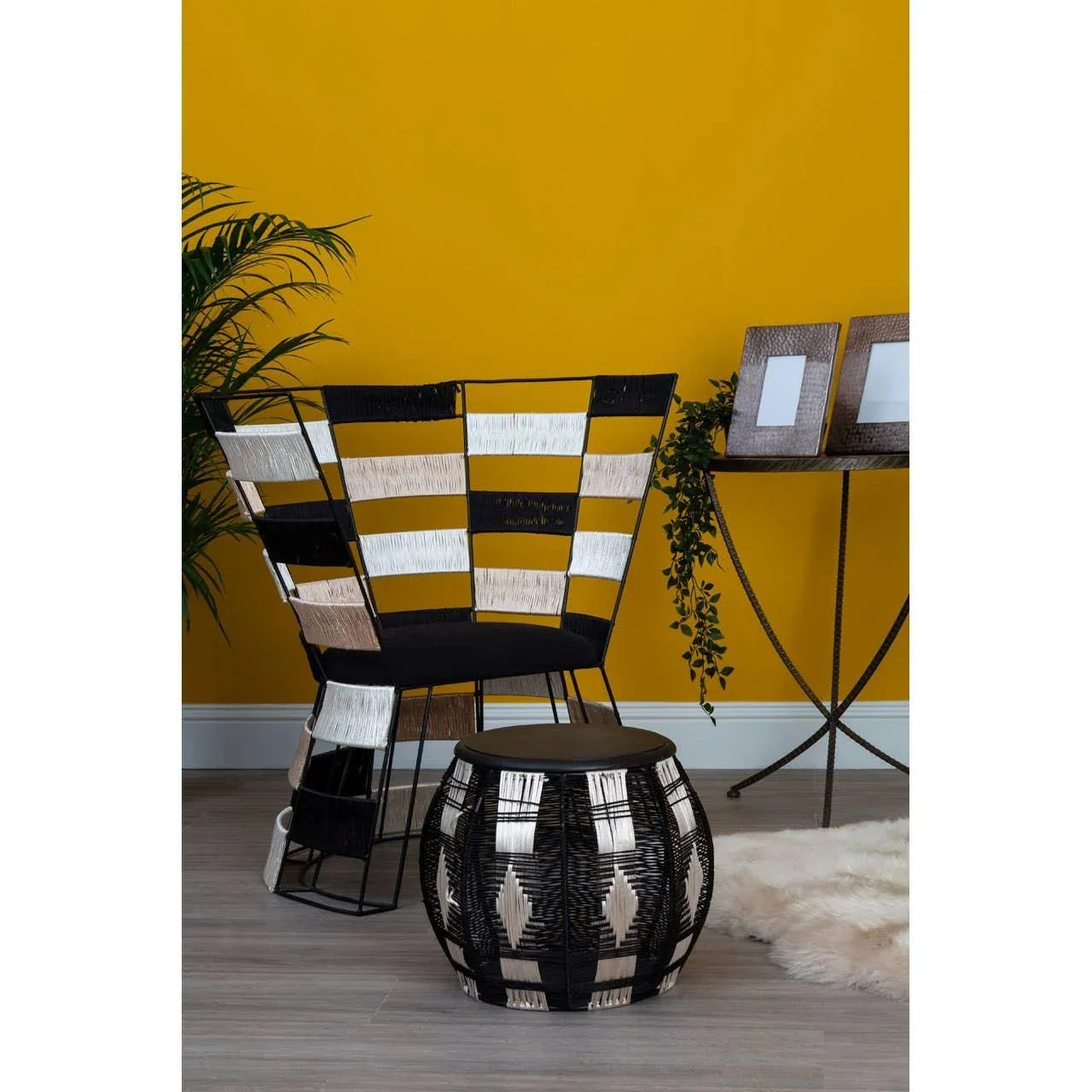 Black and beige woven accent chair with matching round side table against yellow wall