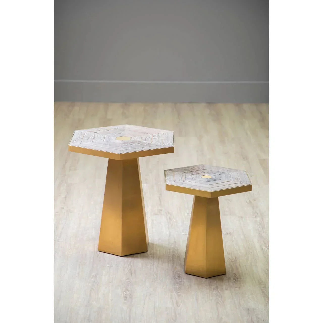 Set of two hexagon side tables with gold bases and wood tops on light flooring