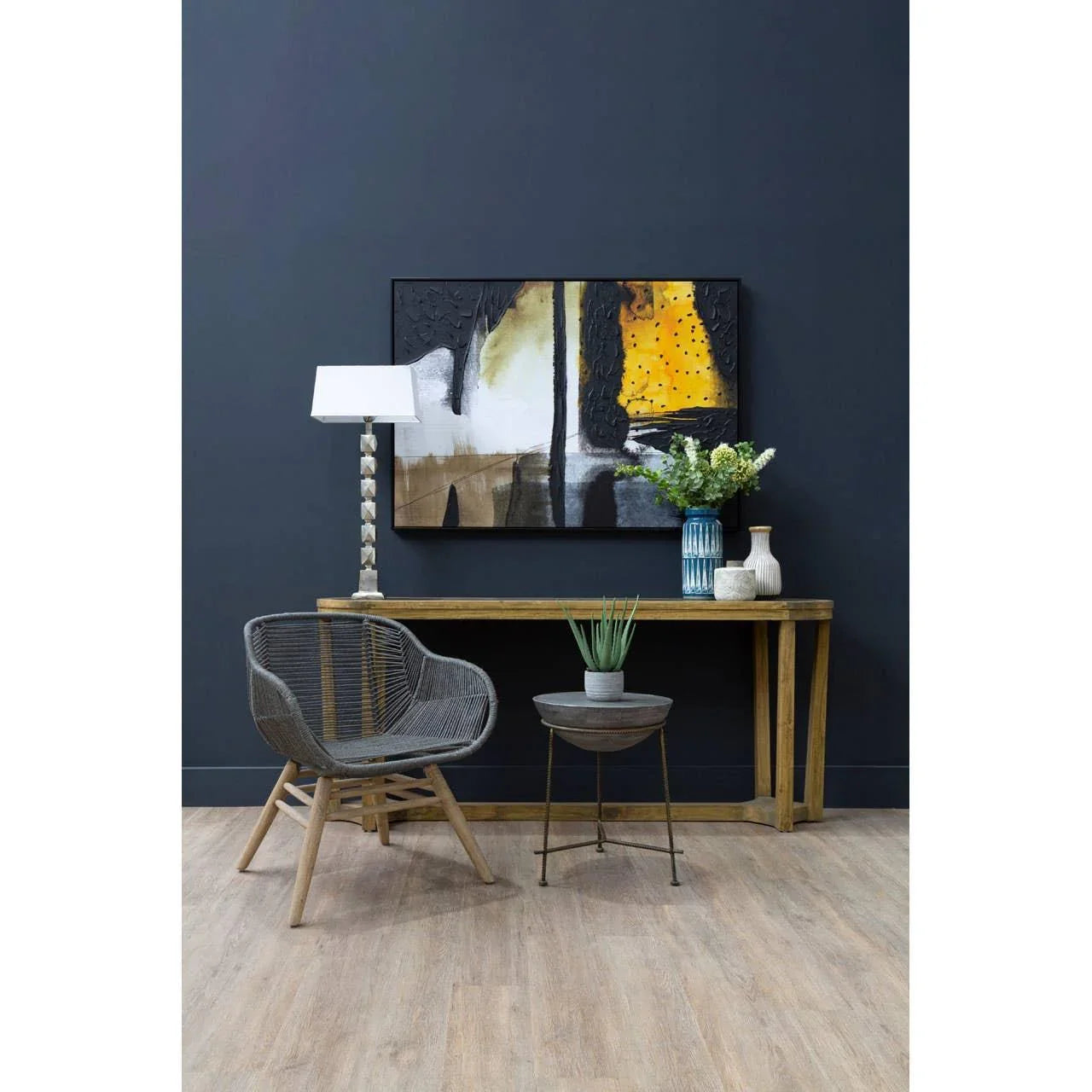 Grey rattan accent chair with wooden legs beside console table and modern decor