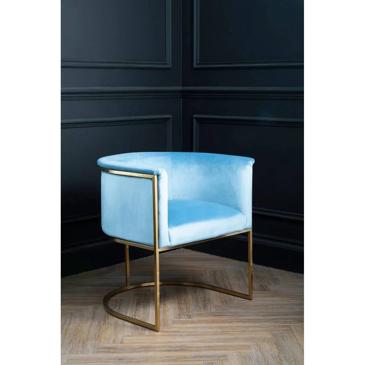 Light blue velvet accent chair with gold metal frame on herringbone wood floor