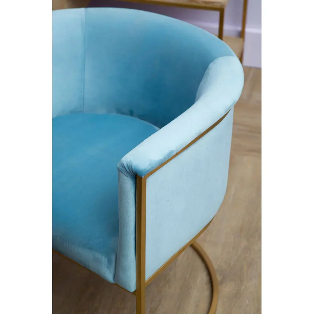 Blue velvet accent chair with gold metal frame on wooden floor