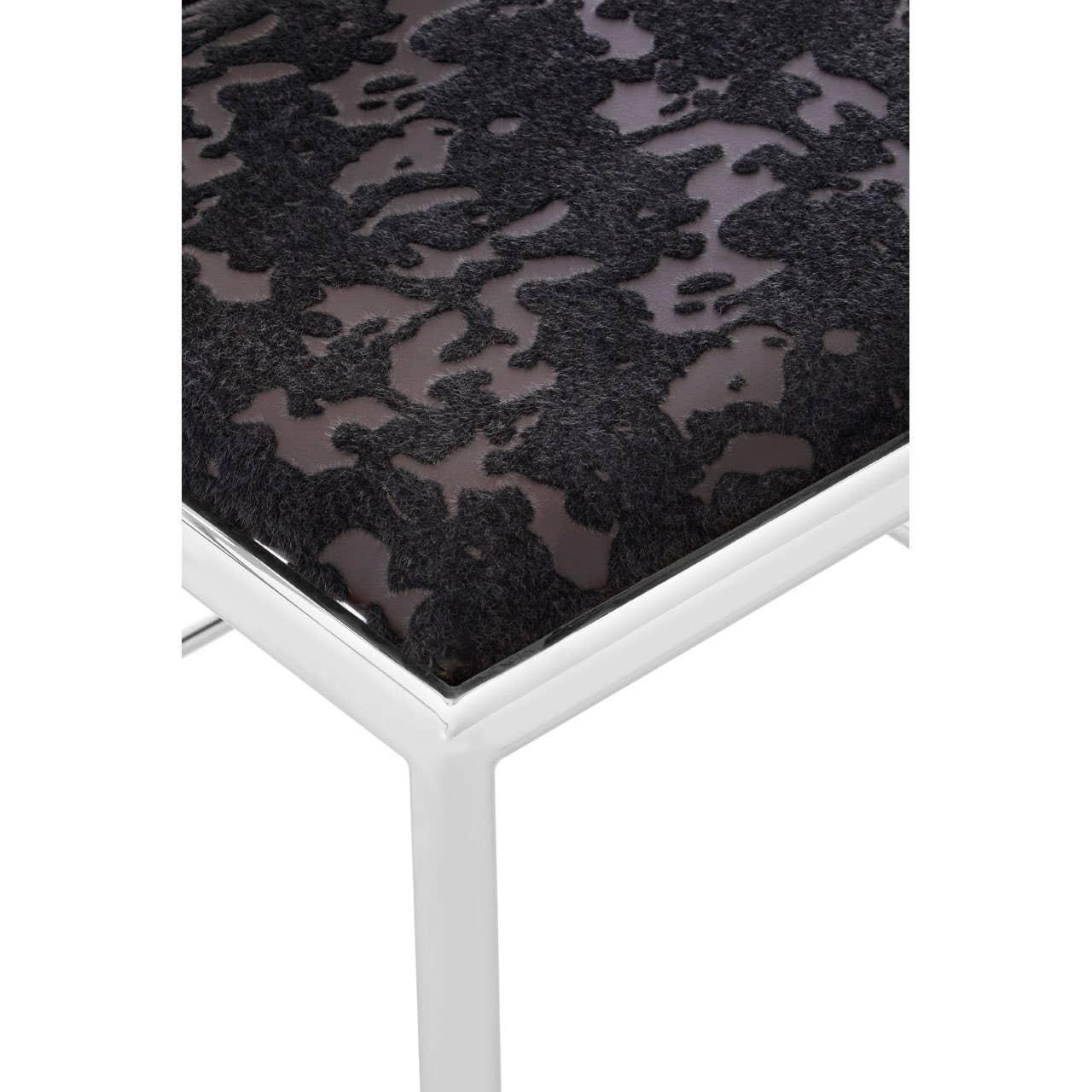 Modern chair with black patterned fabric seat and chrome metal legs, close-up corner view