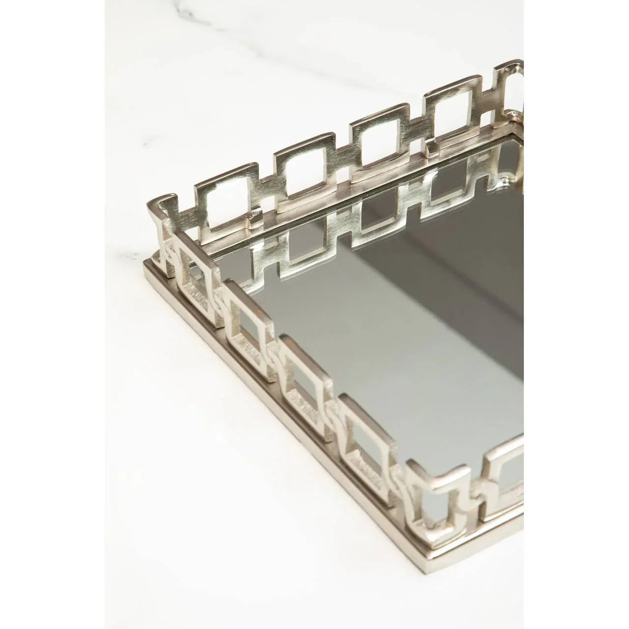 Rectangular mirrored tray with geometric metal border on white surface
