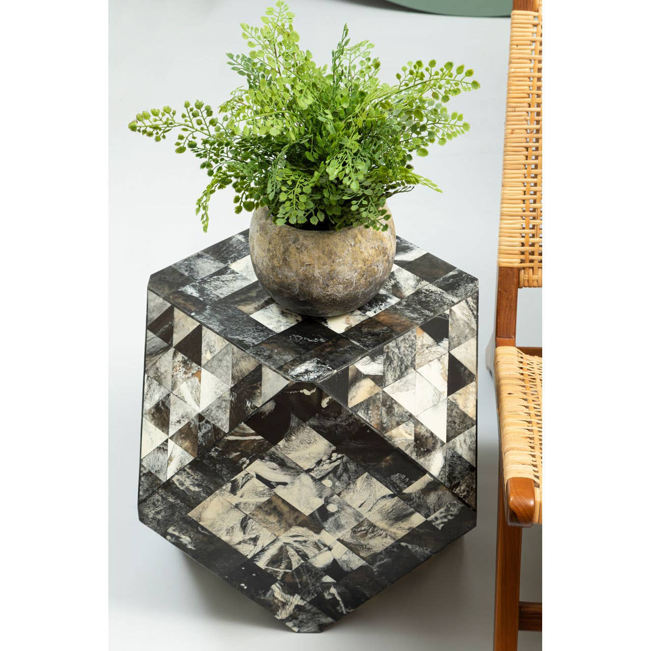 Antique green mosaic geometric hexagon side table with a reflective surface, featuring a small potted plant on top. The table has a unique hexagonal shape and is positioned next to a wooden chair, showcasing its decorative design and functionality in a home setting