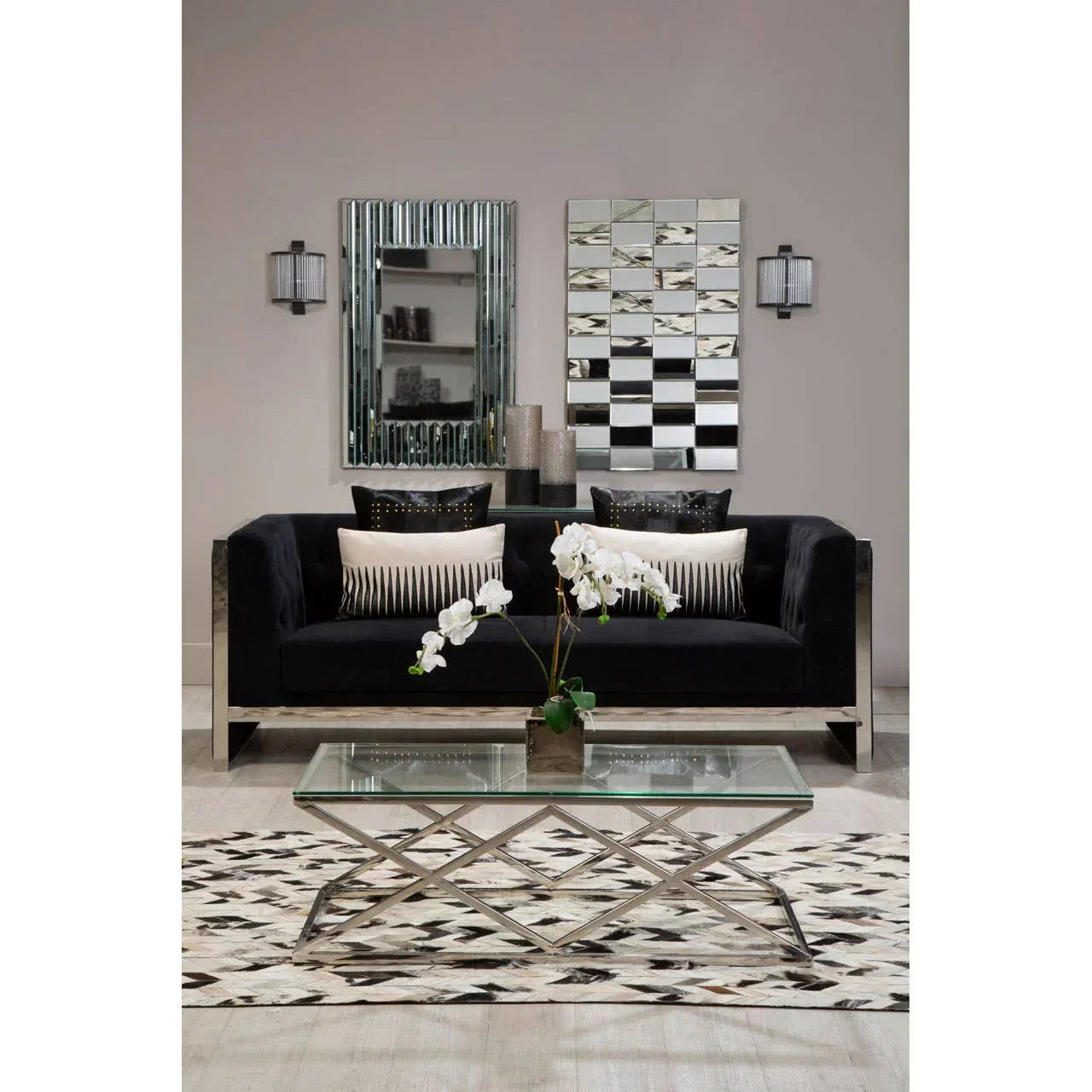 Modern black velvet sofa with chrome frame and cushions, glass coffee table, geometric rug
