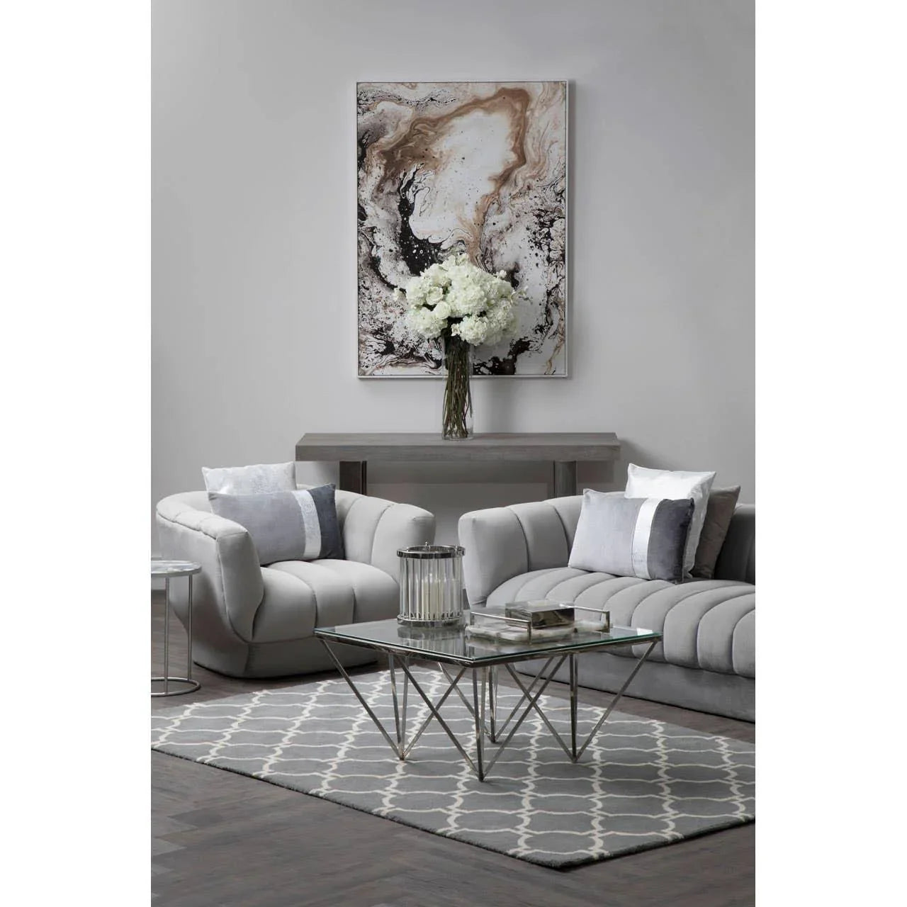 Grey velvet sofa set with glass coffee table and geometric rug in modern living room
