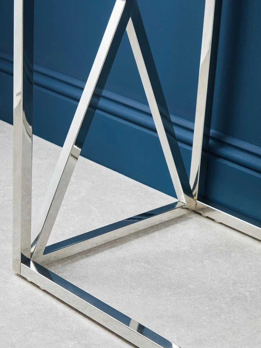 Close up of chrome table legs with geometric design on light tiled floor