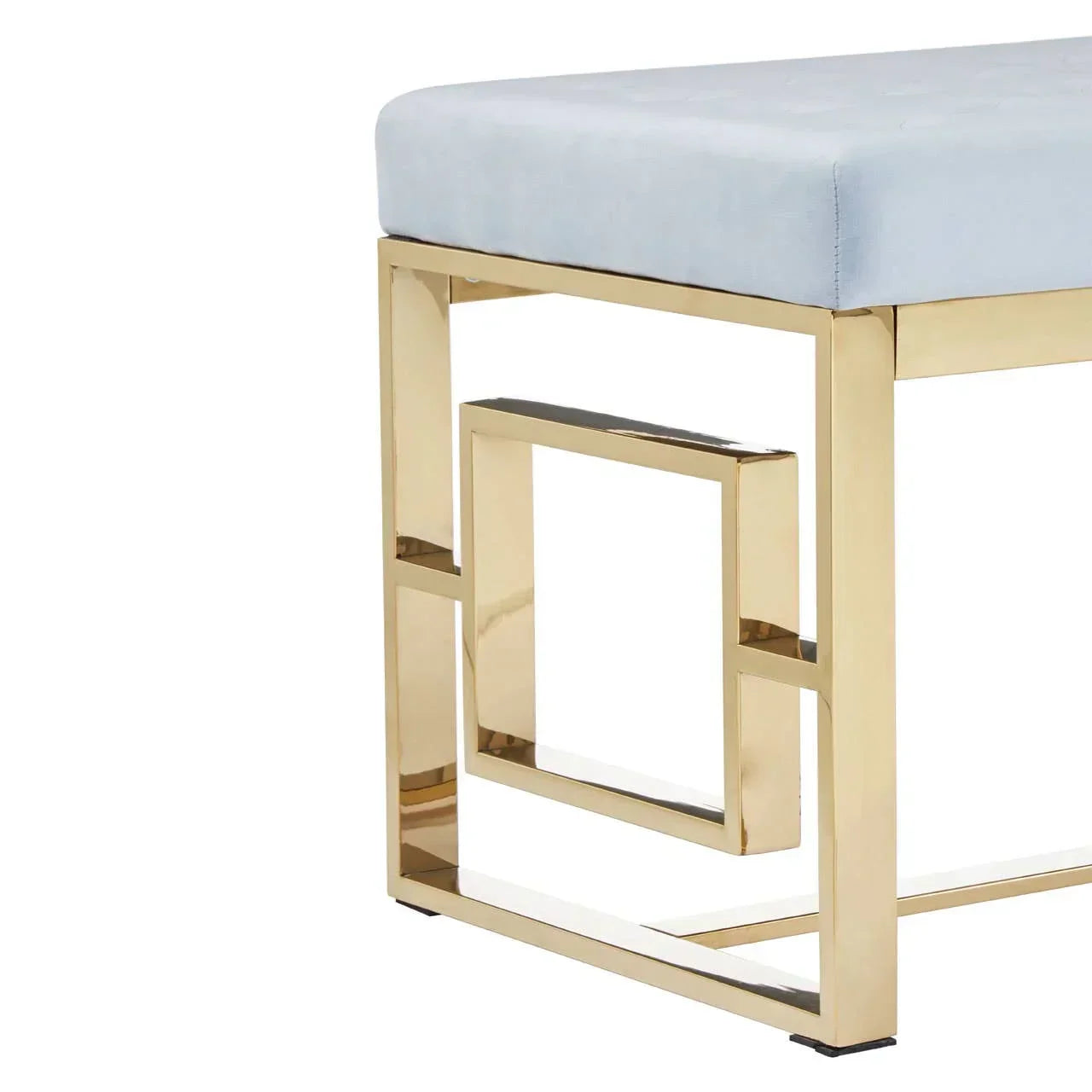 Upholstered bench with gold metal geometric legs and light blue cushioned seat, side view