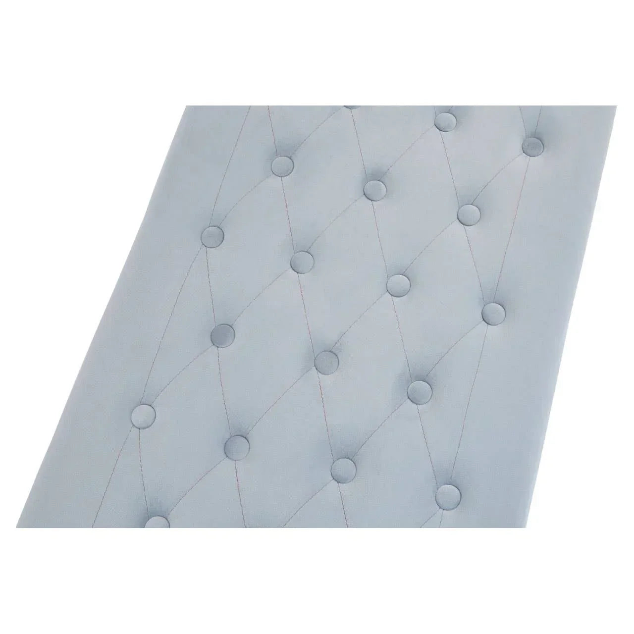 Close-up of light grey upholstered headboard with button tufting