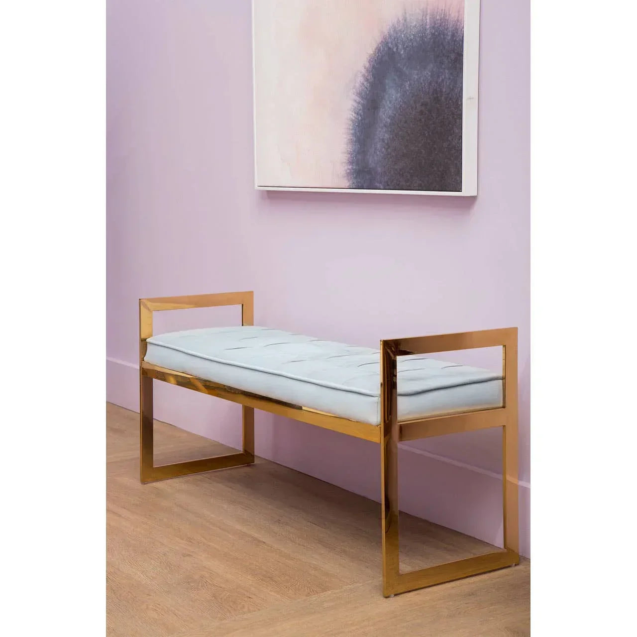 Modern gold frame bench with white cushion against pink wall and abstract artwork