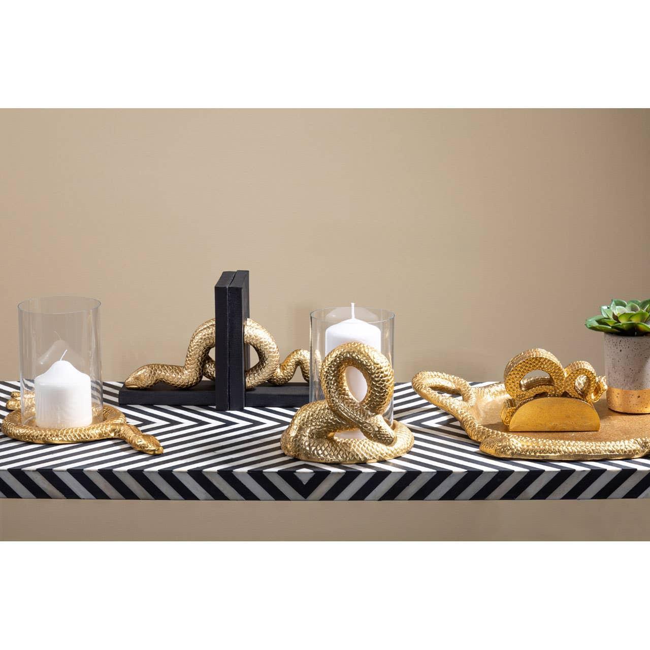 Gold snake ornament candle holders and decor on black and white chevron shelf
