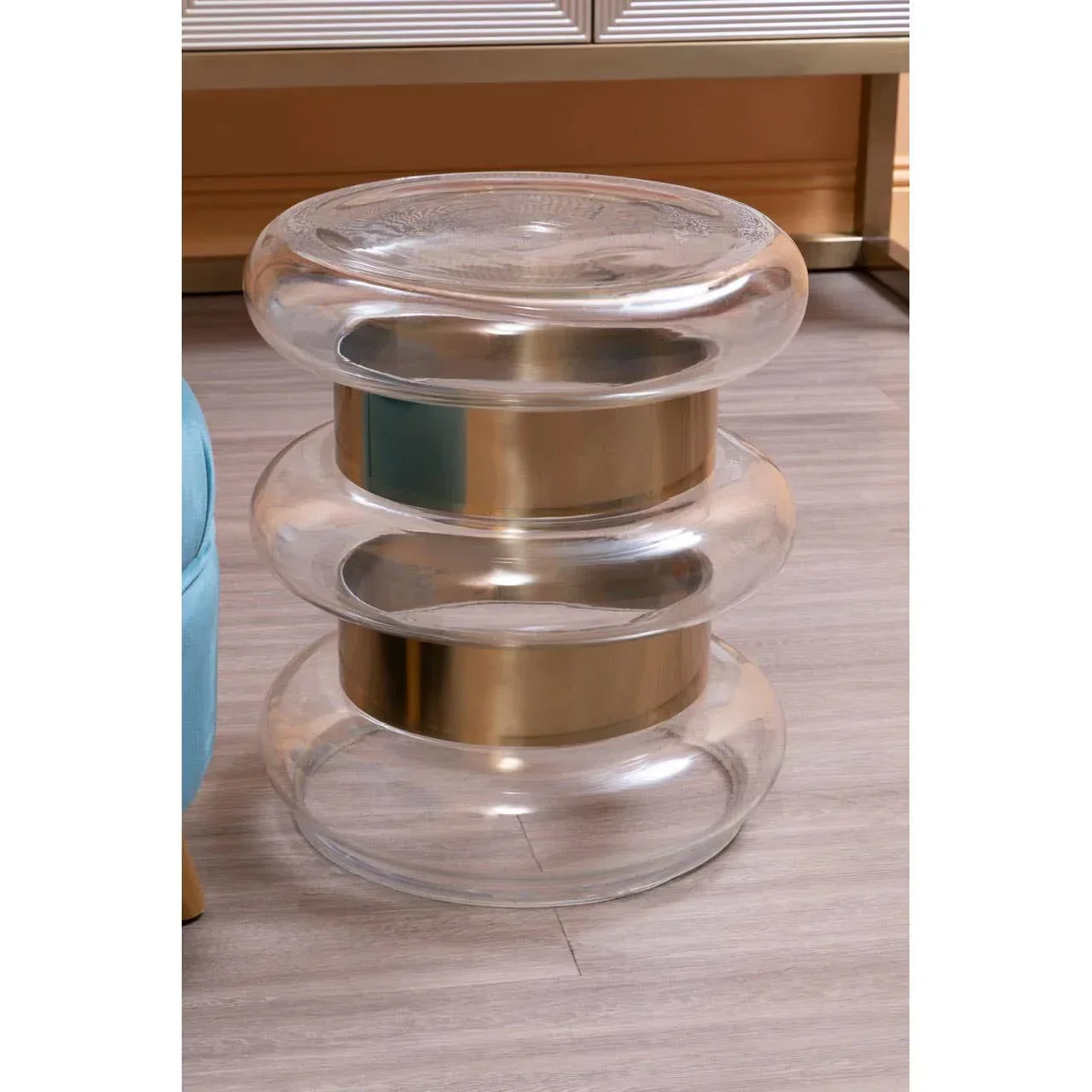 Modern glass side table with gold metallic bands on light wood floor