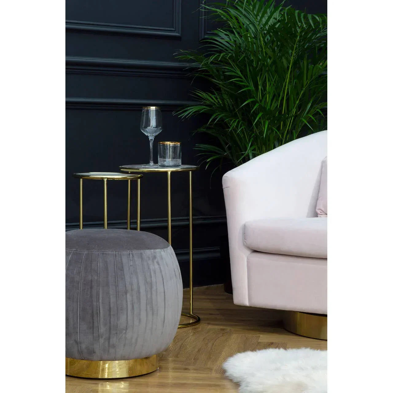 Grey velvet footstool with gold base beside pink sofa and gold side tables in modern living room
