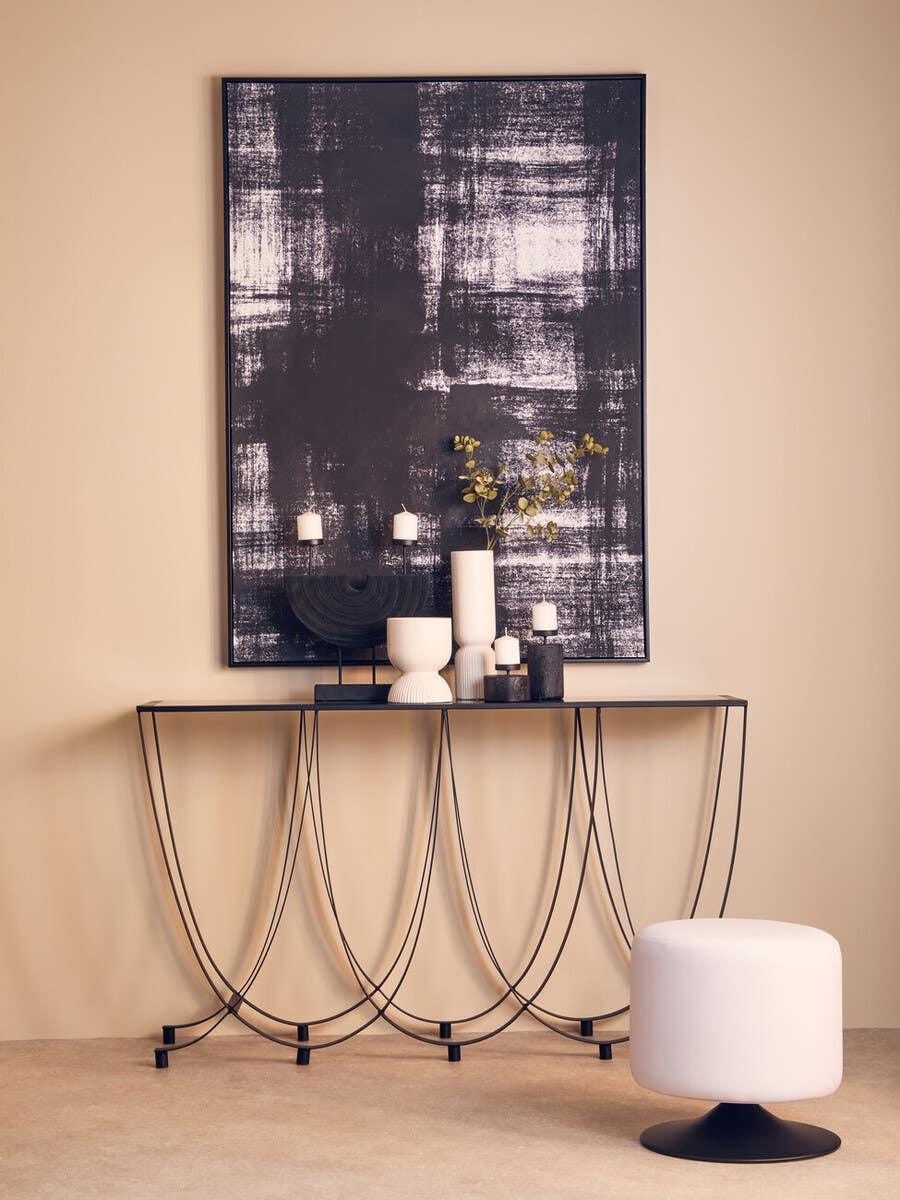Metal console table with curved legs, decorative vases and candles, white round stool in front
