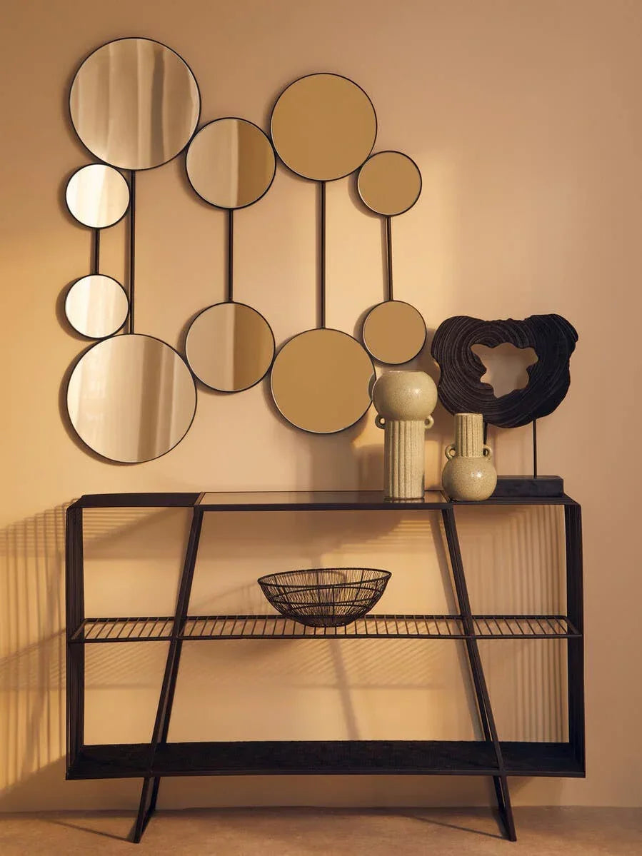 Modern black console table with wire shelf, ceramic vases, and abstract wall mirrors
