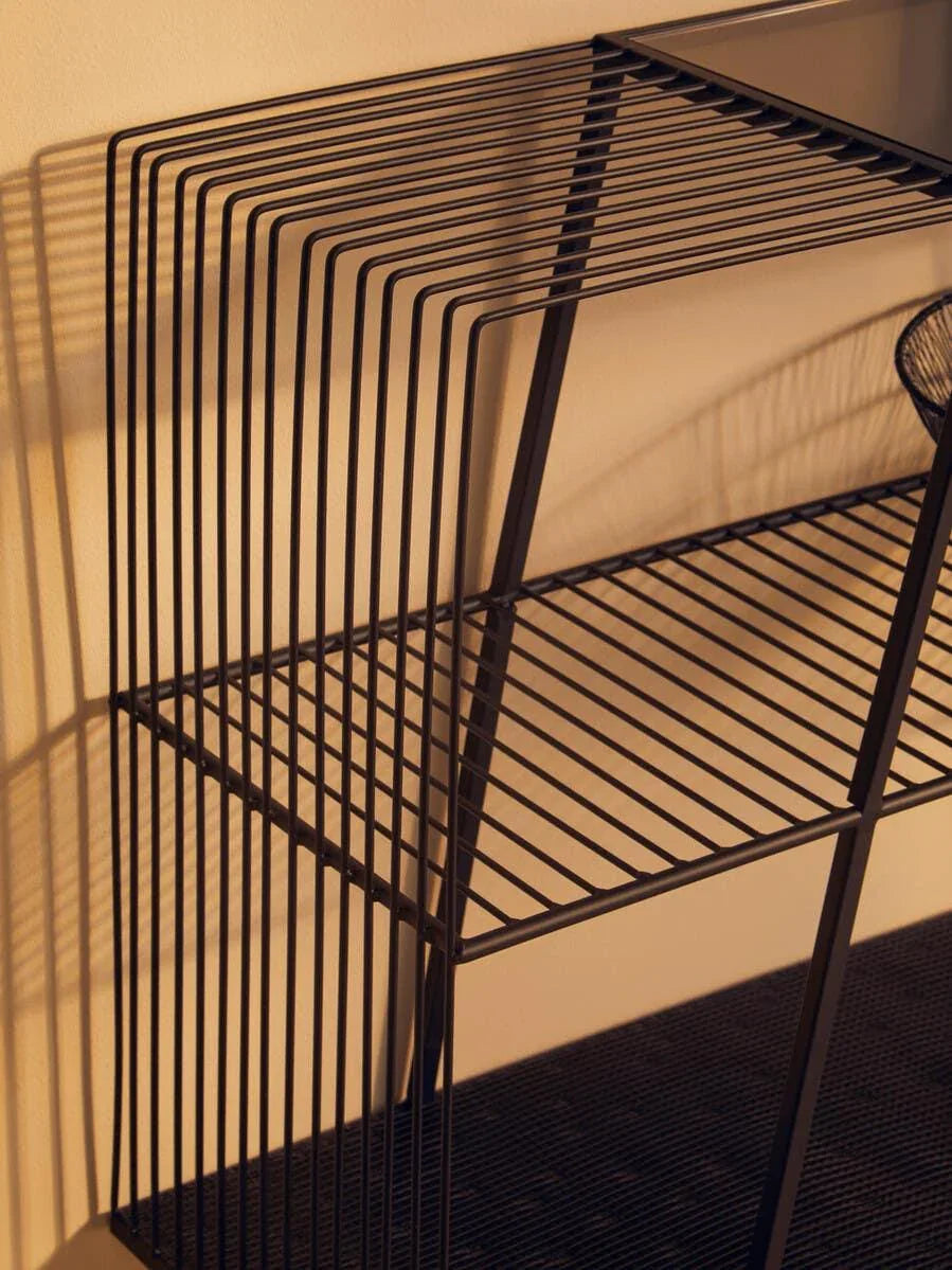 Black metal wire shelving unit with open sides and two tiers against a beige wall