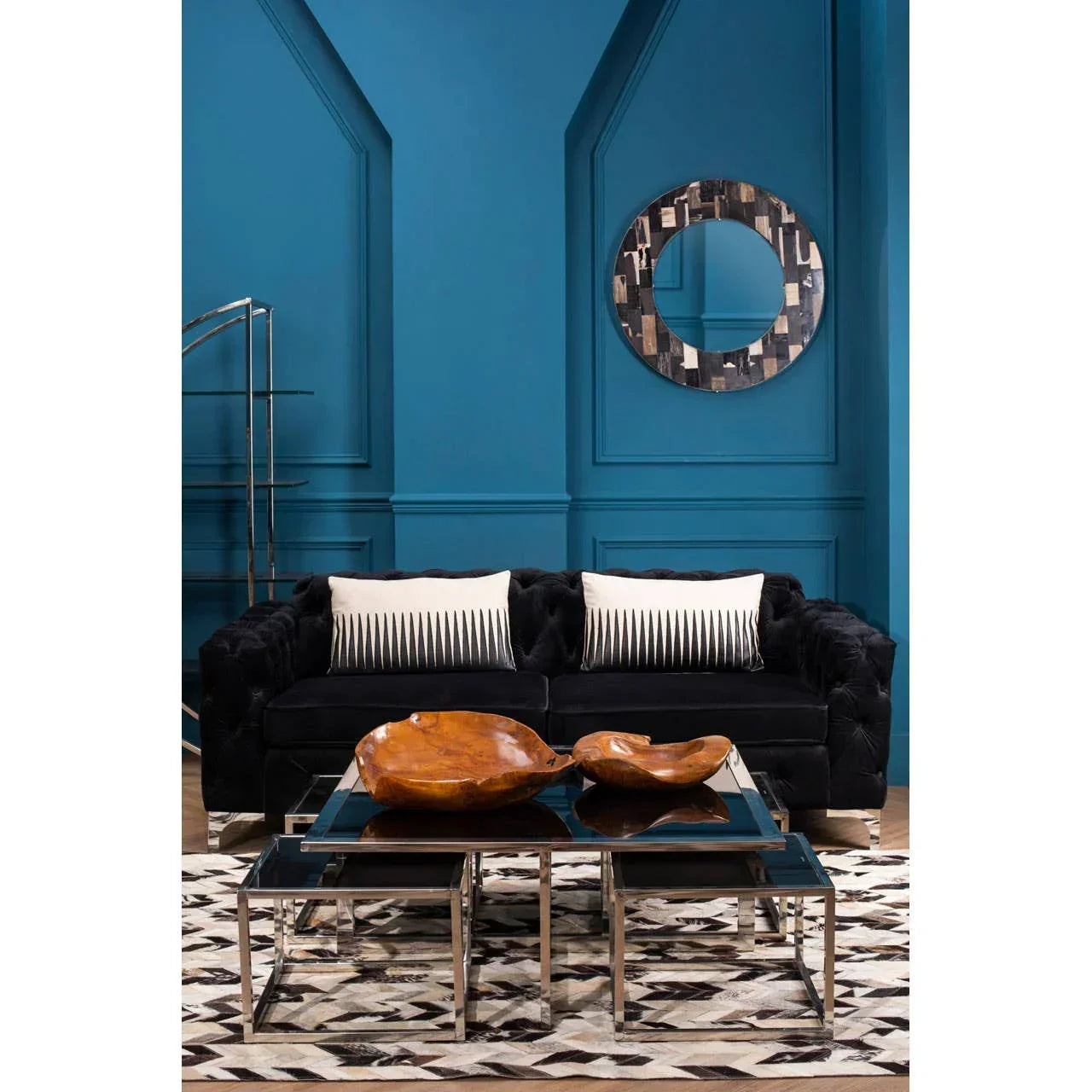 Black velvet sofa with striped cushions, glass coffee table, and geometric rug in modern living room