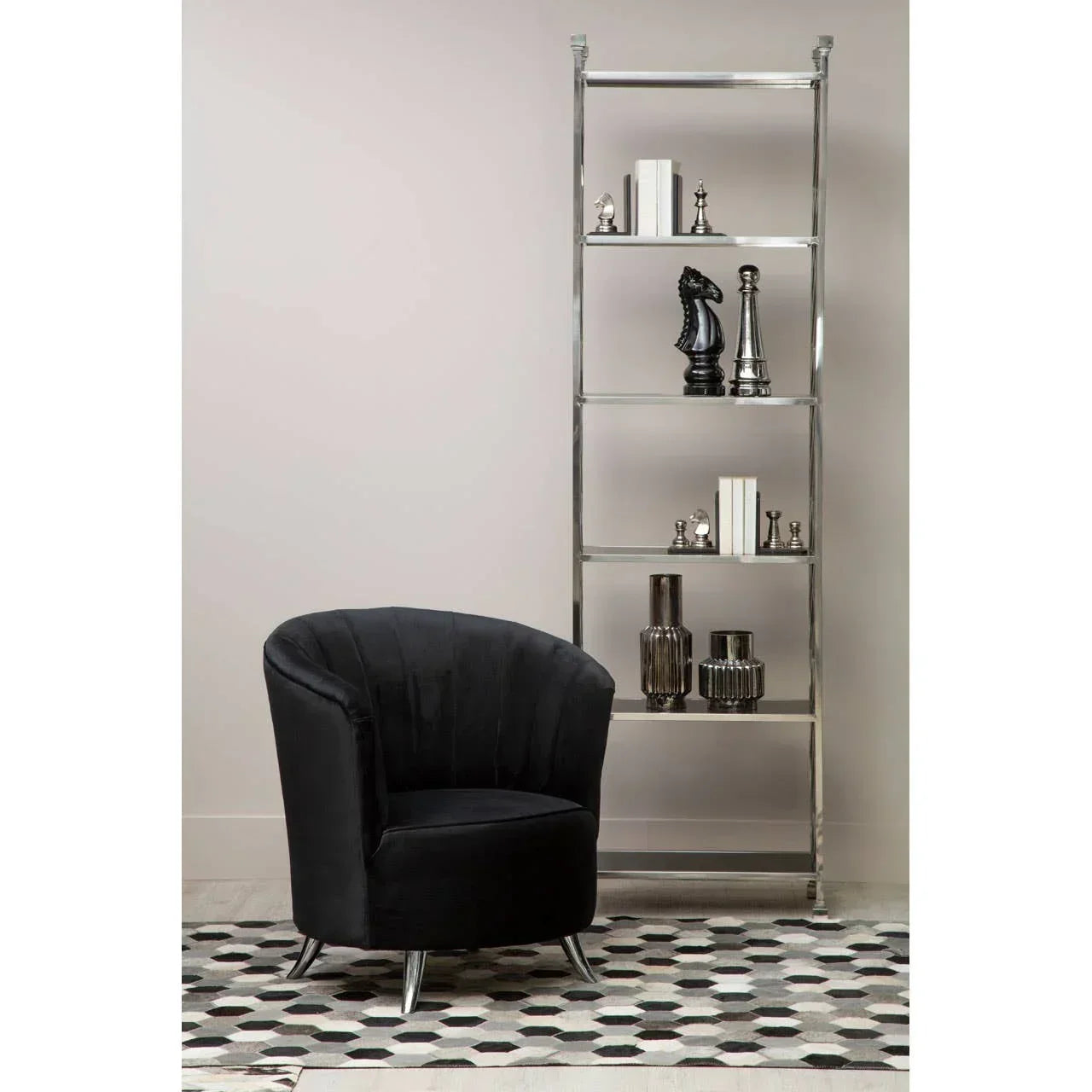 Black velvet accent chair with chrome legs beside modern metal shelving unit and decor items