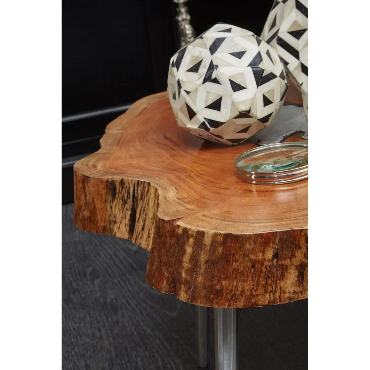 Live edge wooden coffee table with metal legs and geometric decor on dark floor