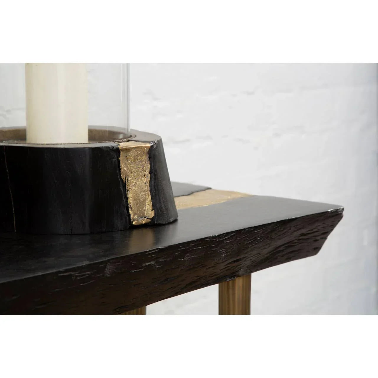 Close view of black wood console table with gold accent and decorative candle holder
