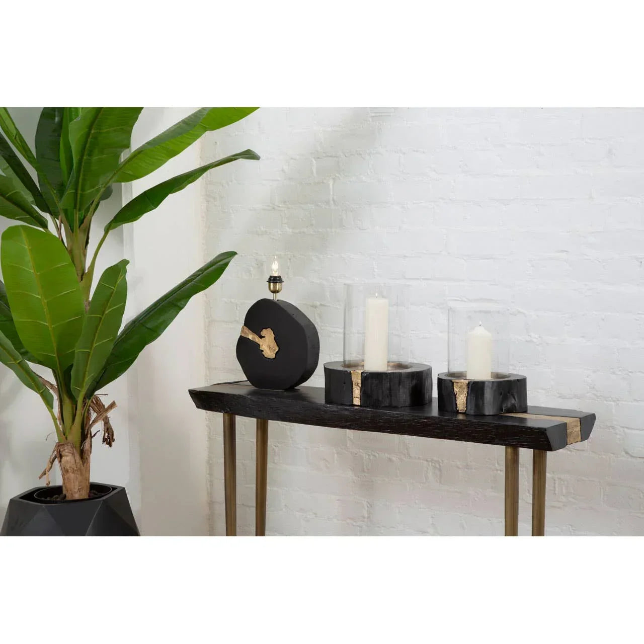 Black wood console table with gold accent, two candle holders and decorative lamp
